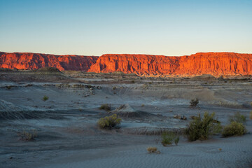 A large red wall of stones bathed in the last rays of the sun in Valle de la Luna natural park in Argentina at sunset