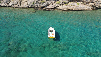 Aerial drone photo of small fishing boat anchored in turquoise clear sea of Mykonos island, Cyclades, Greece