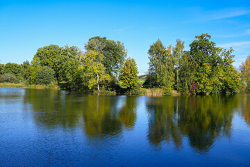 Fototapeta na wymiar Autumn colours on the trees reflecting in a fishing lake at Patsull Park, South Staffordshire
