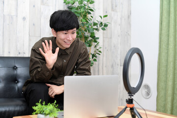 ノートパソコンで動画配信をする若い男性