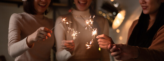 Group of asian friends celebrating christmas party or new year with bengal lights. Friends having fun together at home party.