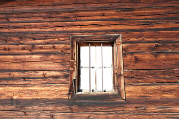 Holzwand einer alten Berghütte mit Fenster als Hintergrund