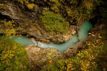 Blick in eine tiefe Schlucht mit einem fließenden Fluss im bunten Herbstwald