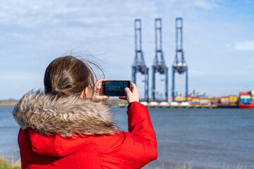Photographer in front of Large steel gantry container cranes in commercial shipping port
