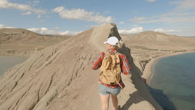 Woman traveler walking on mountain ridge over sea discovering world.