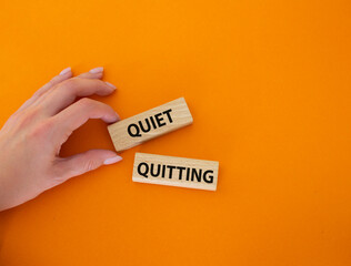 Quiet quitting symbol. Concept word Quiet quitting on wooden blocks. Beautiful orange background. Businessman hand. Business and Quiet quitting concept. Copy space.