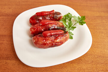Fried sausages with ketchup on a white plate.