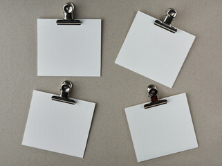 white blank paper notes with metal clips, isolated on gray textured board surface, note or messages...