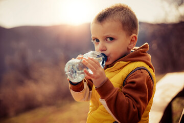 Little boy drinking water in nature