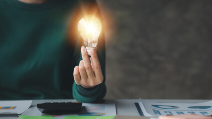 Woman holding glowing lamp, Creative new idea. Innovation, brainstorming, strategizing to make the...