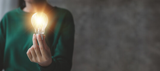 Woman holding glowing lamp, Creative new idea. Innovation, brainstorming, strategizing to make the...