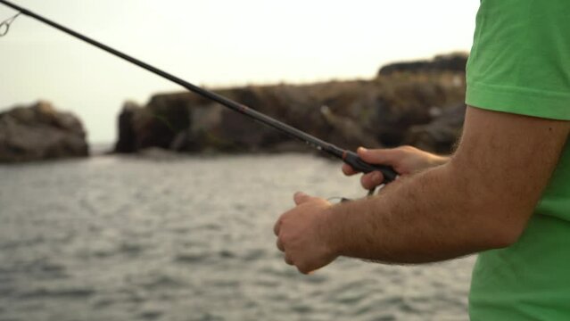 Angler throwing the rod into the sea and picking it up, spinning fishing technique, close-up of the hands and the reel.