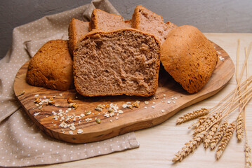 home-baked bread sliced on a wooden board decorated with spikelet and wheat