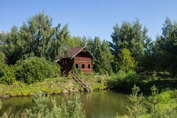 Fototapeta na wymiar Wooden Russian hut on the shore of a pond with a reflection on a sunny summer bright day in Suzdal russia and copy space