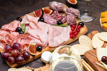 Food antipasto prosciutto ham, salami, olives and grissini bread sticks. cheese on a board parmesan, pecorino, gorgonzola. Charcuterie board. Two glasses of white wine or prosecco
