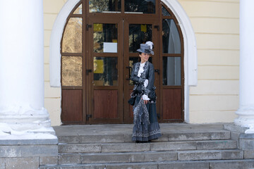 a woman dressed as a 19th century noblewoman stands near an old manor house.russian winter