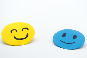 two happy smiling faces, made of blue and yellow paper cut out on a white background. Concept of...