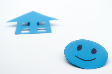 Blue paper cutout smiley face with a blue paper house. on white background. concept of family...