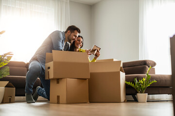 Smiling couple unpaking boxes in new home