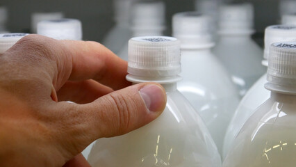 Close-up of many dairy product bottles and a male buyer's hand takes one