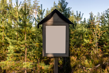 Empty white sign in nature, with green trees in the background