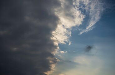 This photo captures a moody afternoon sky with big clouds as a storm is about to roll in over the blue sky. 