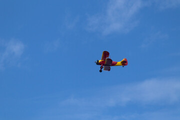 Little red biplane flying across semi cloudy sky. This plane almost reminded me of the red baron....