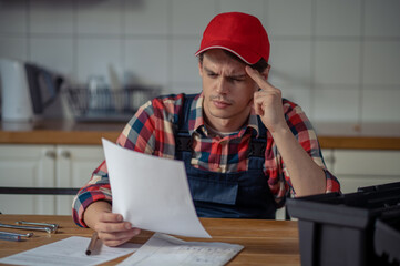 Focused serviceman dressed in workwear perusing installation instructions