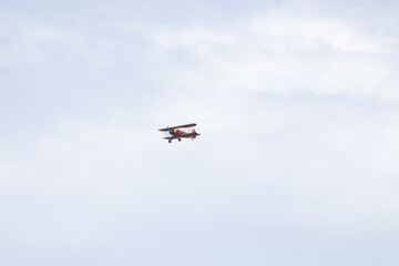 Little red biplane flying across semi cloudy sky. This plane almost reminded me of the red baron....