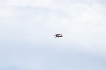 Fototapeta na wymiar Little red biplane flying across semi cloudy sky. This plane almost reminded me of the red baron. It has such an old look to it. I took this picture while standing on the beach in Cape May New Jersey.