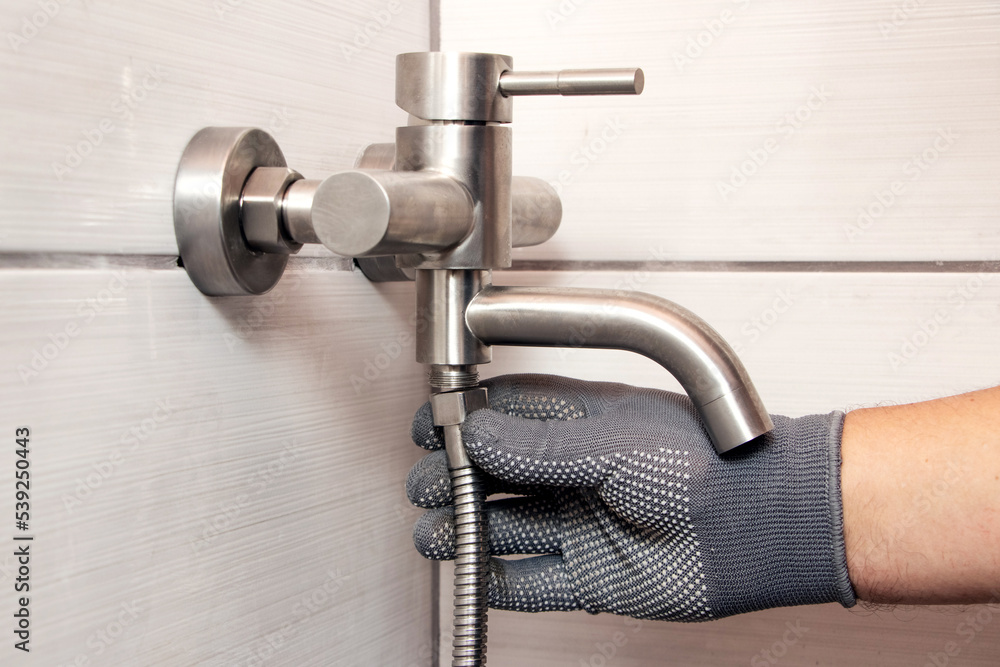 Wall mural a plumber connects a hose to a faucet in a bathroom