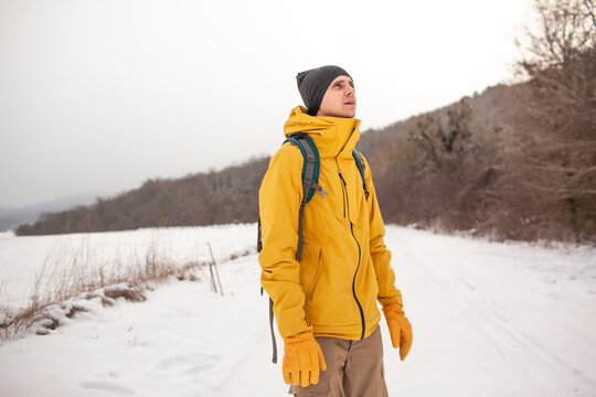 The man dresssed yellow warm jacket and trousers, bagpack traveling in the snow landscape