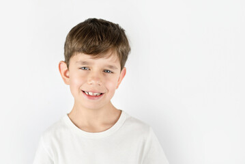 A young boy smiles nicely on a light background, the boy has a nice smile but not all his teeth are healthy, his teeth are decaying from sweets, he needs to go to dentist, dental concept