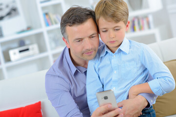 Fototapeta premium Adult and child looking at cellphone