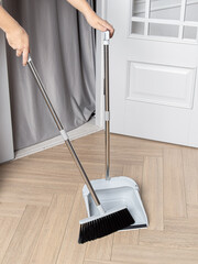 Gray dustpan and broom brush for dry cleaning in the apartment. Cleaning service utensils. Woman sweeps the floor