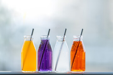 Colored bottled drinks on a blurry background, open space, white, light blue, yellow, orange. purple, alcohol, not alcohol