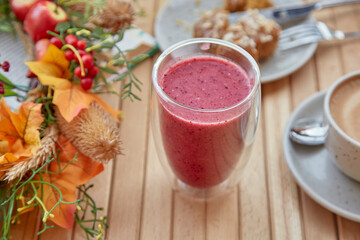 Healthy autumn lunch time - pink raspberry smoothie, cup of coffee and dessert among autumn decorations