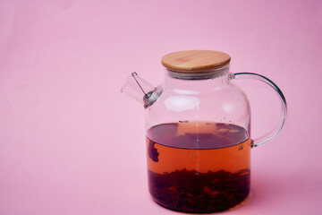 tea in a transparent glass teapot on a pink background