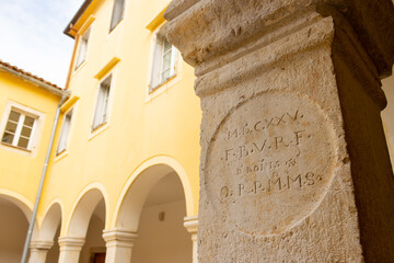 An inscription on a pilar of the Franciscan monastery in the town of Krk on the island Krk in Croatia.