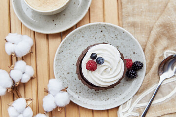 French cupcake with cup of coffee outside. Aesthetic cotton decoration. Cozy breakfast