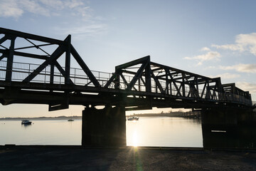 Fototapeta na wymiar Sunrise glows through Tauranga Railway bridge silhouette