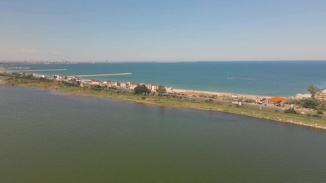 Aerial video taken from a drone at Eforie beach with Techirghiol lake on the back side of the beach and the Black sea on the front side. A patch of land between sea and lake seen from above.