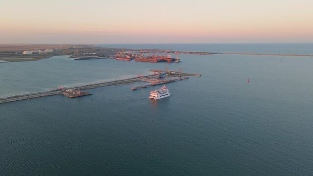 Aerial view of a harbor with ships sailing and docked. Footage was taken from a drone at a higher altitude in summer season at sunset in Navodari harbour, Romania.