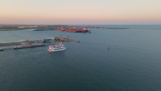 Aerial view of a harbor with ships sailing and docked. Footage was taken from a drone at a higher altitude in summer season at sunset in Navodari harbour, Romania.