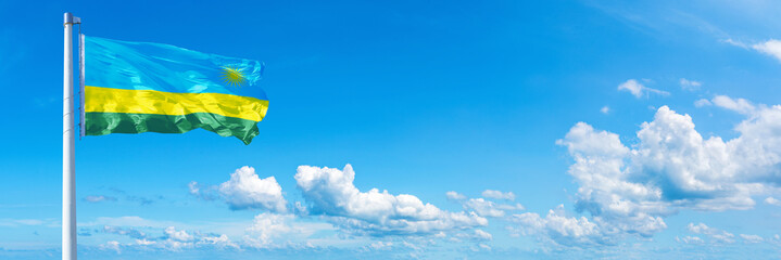Rwanda flag waving on a blue sky in beautiful clouds - Horizontal banner
