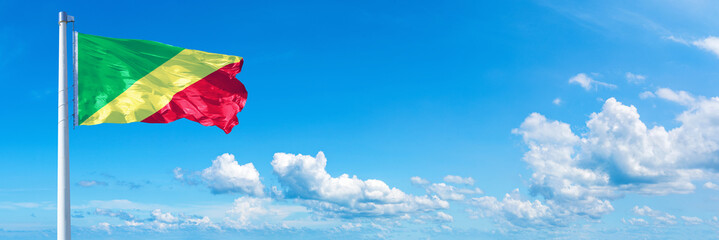 Congo flag waving on a blue sky in beautiful clouds - Horizontal banner