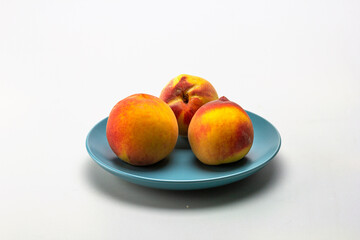 ripe peaches on a shallow plate, on a white milky background.
