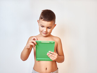 A little boy with a bare torso makes a note on a tablet.