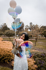 Mujer latina  parada sonriendo con globos en la mano y burbujas de agua en el aire  - obrazy, fototapety, plakaty