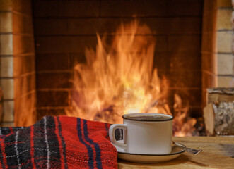 A mug of tea and woolen thing near a cozy fireplace, in a country house, winter or autumn holidays